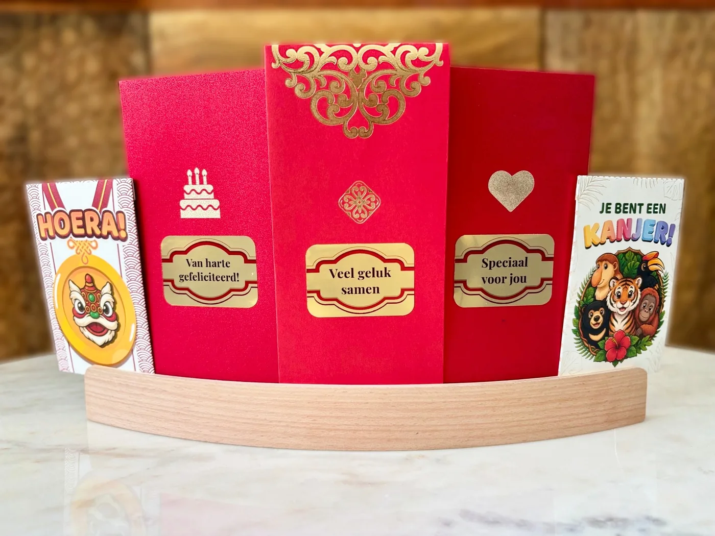 The Mandarin Leaf angpao collection: red envelopes with gold blessings in Dutch, standing in a wooden holder